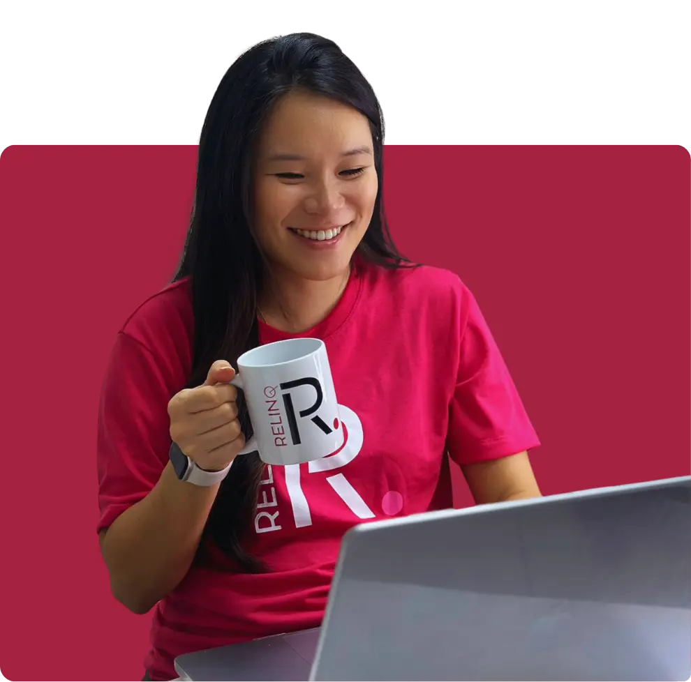 Uma menina feliz olhando para o computador e segurando uma caneca da Relinq